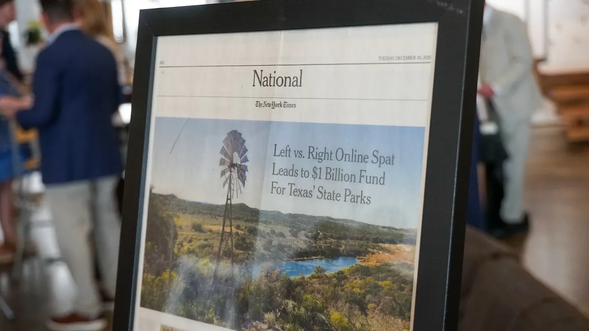 A framed event display photographed with guests in the background