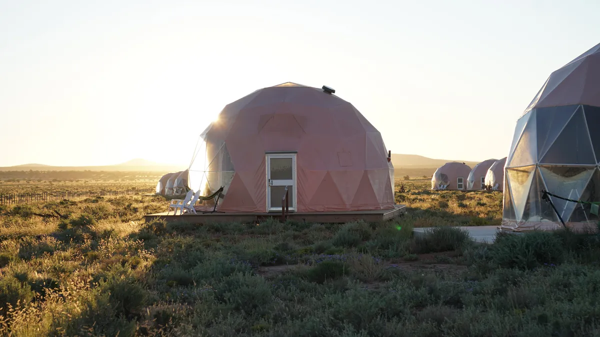 Geodesic guest domes in a grassy landscape at sunset